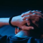 boy facing away with hands on his head in one handcuff