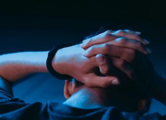 boy facing away with hands on his head in one handcuff