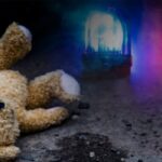 A teddy on the ground with emergency lights in the background