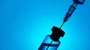 shadowy syringe with bottle on blue background